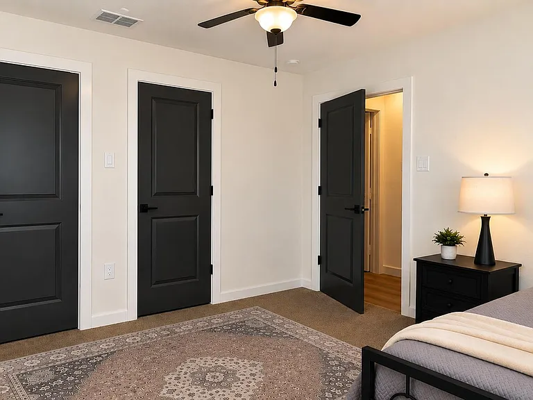Bedroom with ceiling fan, carpeted flooring, and a nightstand with lamp, plus easy access to the hallway.