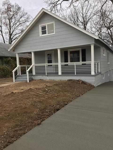 Street view of house with driveway leading to large parking pad in back of house