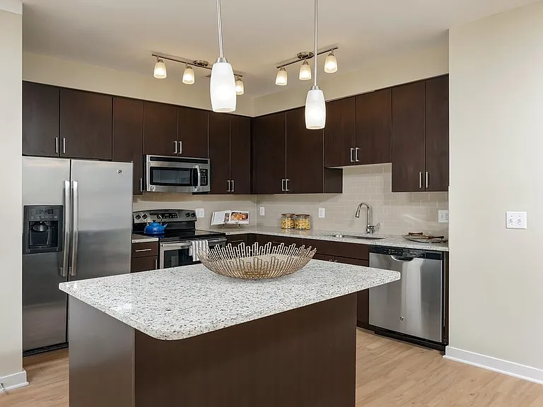 Classic Package II townhome kitchen with stainless steel appliances, espresso cabinetry, white speckled granite countertops, and hard surface flooring