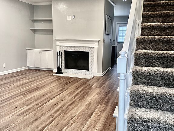 Newly remodeled living room in 2025. New floors, paint, carpet, electrical, fan, windows, door, and serviced fireplace.
