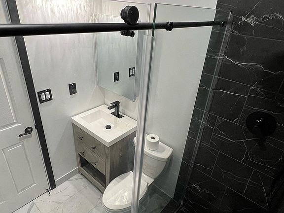 Bright bathroom view showcasing a stylish vanity, energy-efficient motion-sensor lighting, an overhead vent with built-in speaker, fully mirrored medicine cabinet, and a modern towel rack_all designed with comfort and functionality in mind.