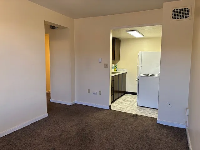 unit 312 living room with carpet kitchen has white appliances rent is 1185.00