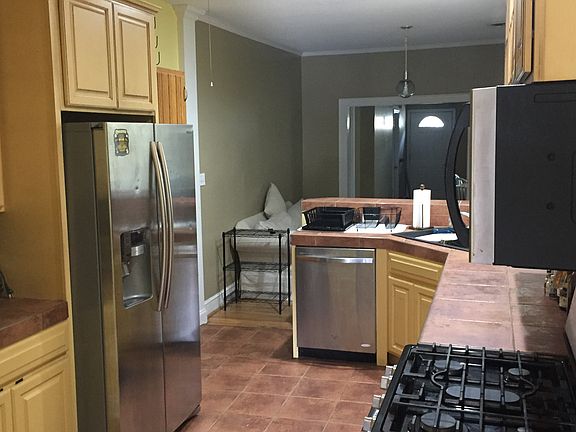 Kitchen with all stainless steel appliances, ceramic countertops, and bar