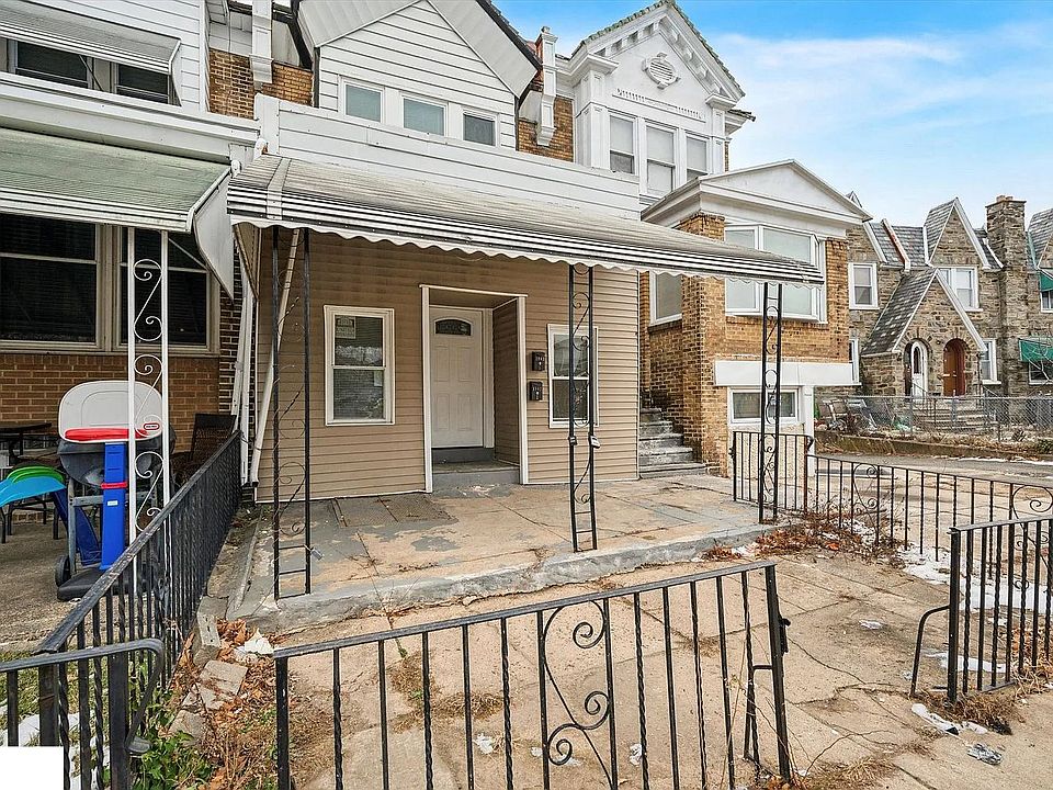 Brick-front duplex with a covered porch and gated front entry. Situated on a quiet residential block with street parking available. A small outdoor space at the front offers added convenience and versatility.