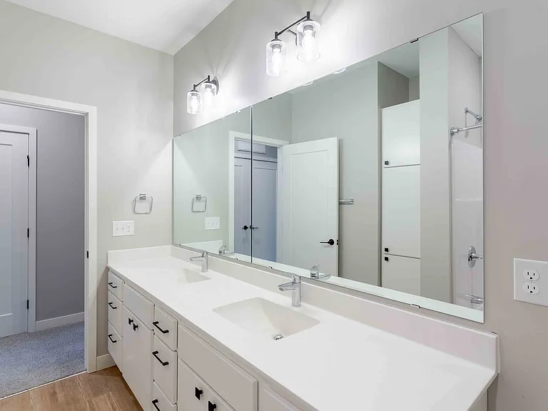 Elegant modern bathroom with double sinks, large mirror, and ambient lighting.