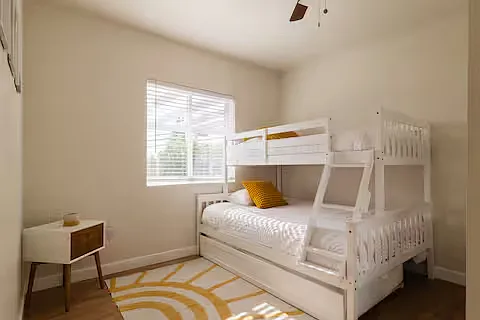 Bedroom built for fun! With a single-over-double bunk bed plus trundle, soft, cozy bedding, and plenty of sunlight, it's a perfect hangout for kids. Sleepovers, group stays, or just chilling_this room makes it all comfy and playful.