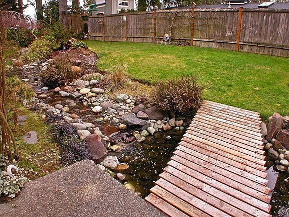 The platformed entry walkway provides a splendid view of the front yard water feature, with small wa