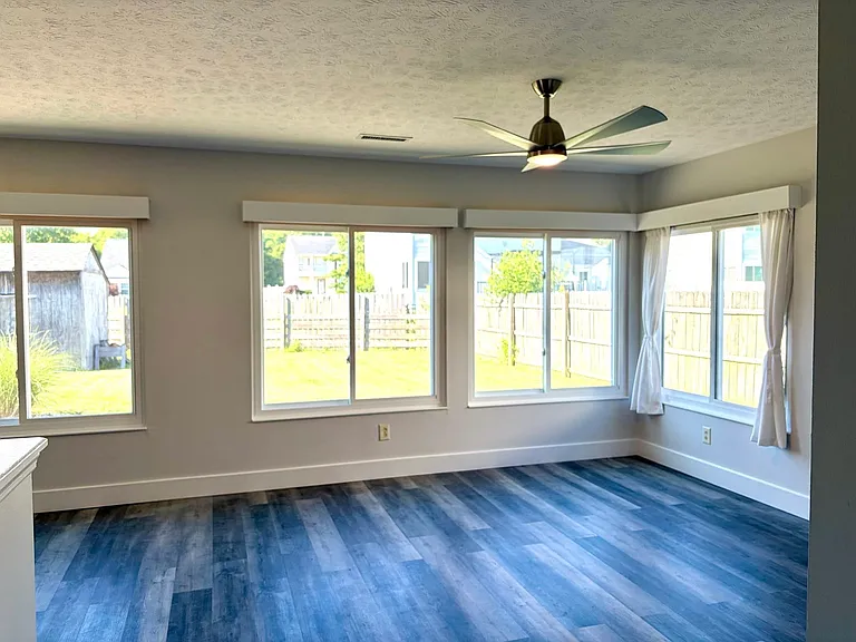 Large living and dining area with huge windows, overlooking fanced back yard, High end ceiling fan, flat screen tv mount and solid surface flooring.