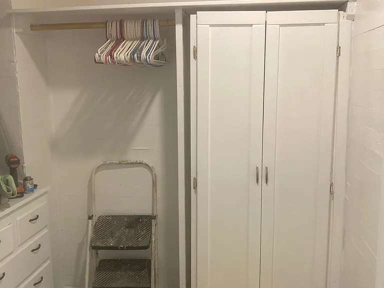 The walk-in closet to the main bedroom with flexibility and storage. A storage closet with shelves, a built in set of drawer with storage shelves above. There are two doors, one to the master bedroom and one to the hall leading to th bathroom/kitchen