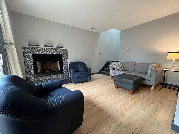 Cozy living room, fireplace, blackout curtains over south-facing sliding doors, skylight above the stairs also opens.
