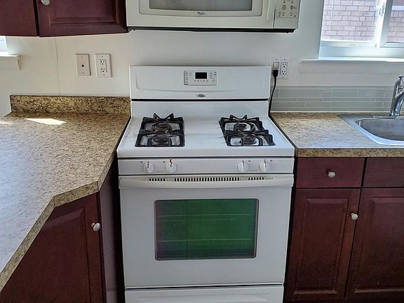 View of kitchen cooking area with gas stove and microwave.