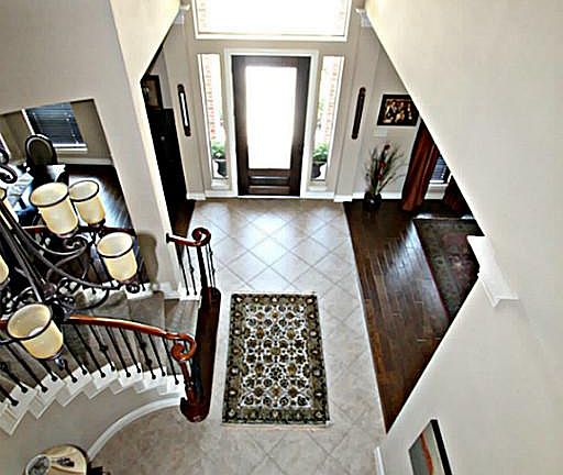 OPEN THE DOOR TO THE SOARING FOYER PRESENTING UPGRADED TILE FLOORS ON THE DIAGONAL, WROUGHT IRON SPINDLES, AN ART NICHE, AND A LOVELY CHANDELIER