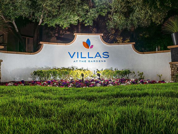 Villas at the Gardens Illuminated Entry Sign with Lush Lawn and Colorful Flowers