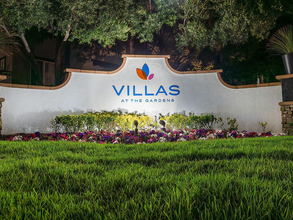 Villas at the Gardens Illuminated Entry Sign with Lush Lawn and Colorful Flowers