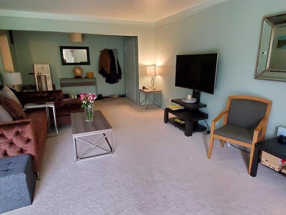 Living room with a tv and tv console, velvet sectional sofa, coffee table, big fancy mirror, and more as seen in the picture.