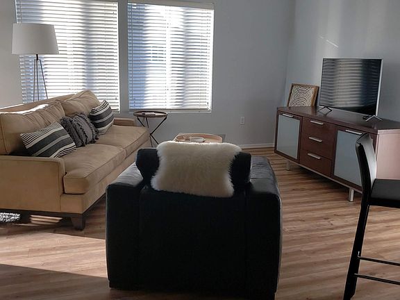 The living room features big windows with coverings, sliding door to a spacious balcony, a gas fireplace, and furnishings.