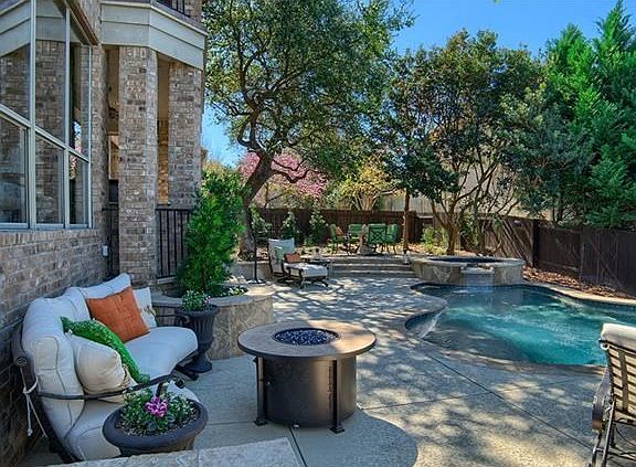 The resort style backyard with refreshing pool, hot tub, outdoor kitchen and television will without