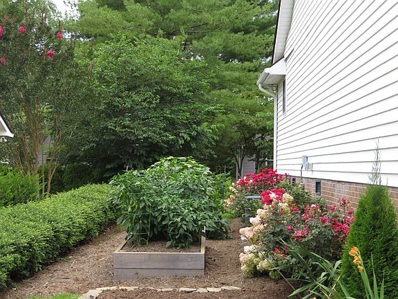 Southside of the home with a rock wall garden and two 8' by 4' raised beds for gardening.