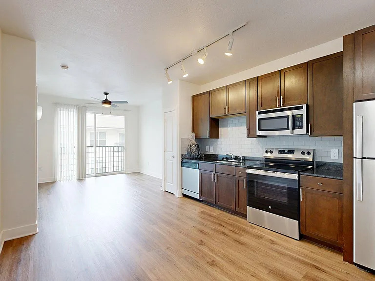 Apartment kitchen with stainless steel appliances, dark counters, and wood style floor.