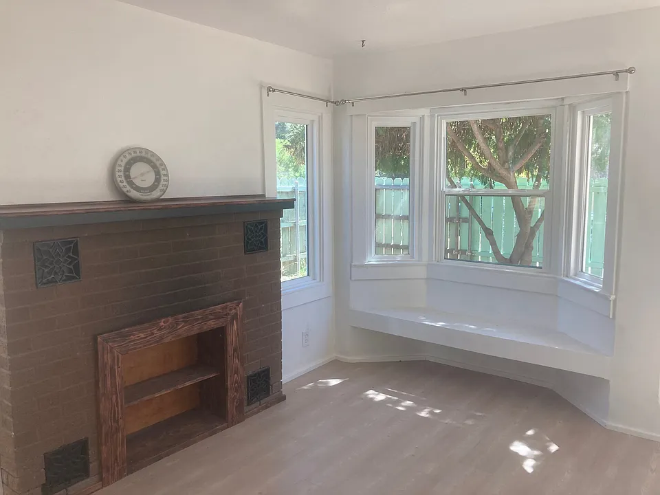 Southwest corner of the front room A custom made bookcase was installed jn the non-functional fireplace. A window seat with a storage area is to the right