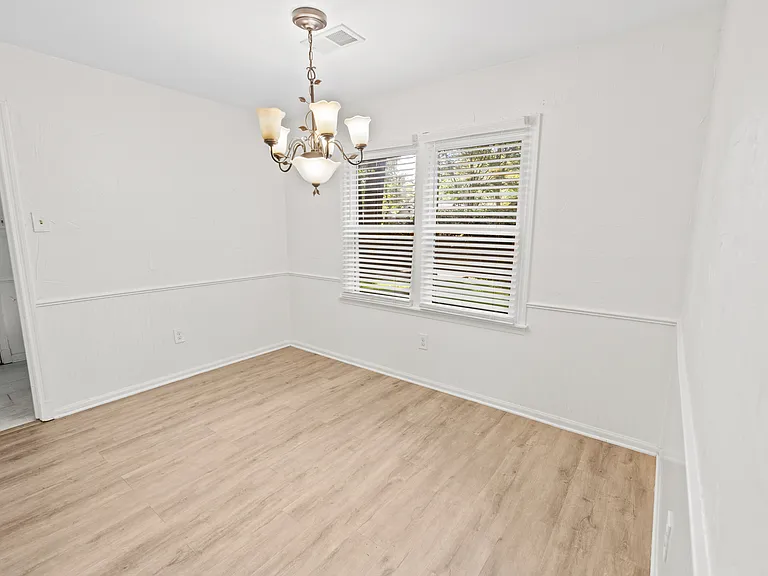 Elegant dining room with classic chandelier, chair rail molding, hardwood floors, and natural light _ ideal for family dinners.