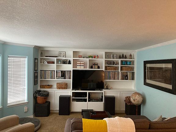 Living room with South Facing Bay window & Custom built in. Wired for surround sound.