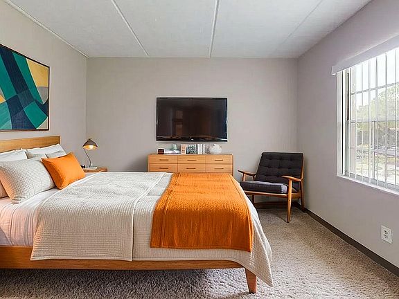 Modern bedroom with cozy double bed, vibrant decor, large window with natural light, and stylish furnishings.