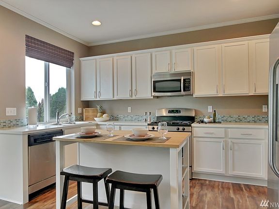 Light/Bright Kitchen with newly refinished cabinetry, mosaic backsplash & stainless appliances, custom window treatments