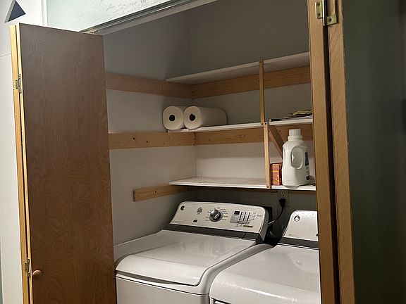 Utility room with storage above and washer and dryer.