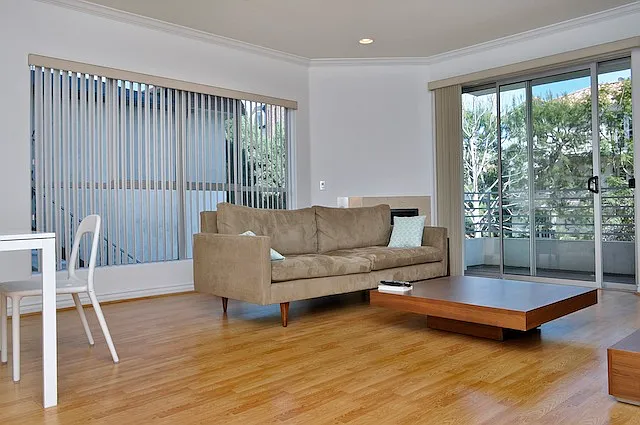 Open living/dining/kitchen looking at balcony with prior tenant's furniture
