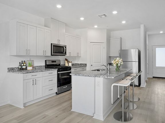 The kitchen has stainless steel appliances and plank flooring.