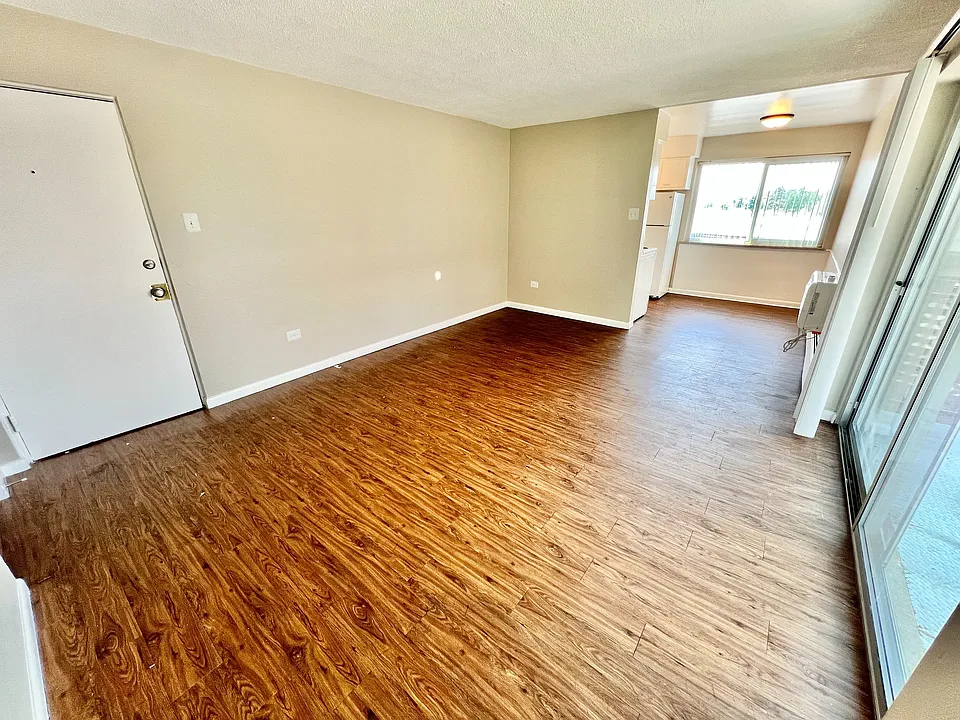 Bright and airy living space with stylish wood flooring, large windows, and an open layout perfect for modern living.