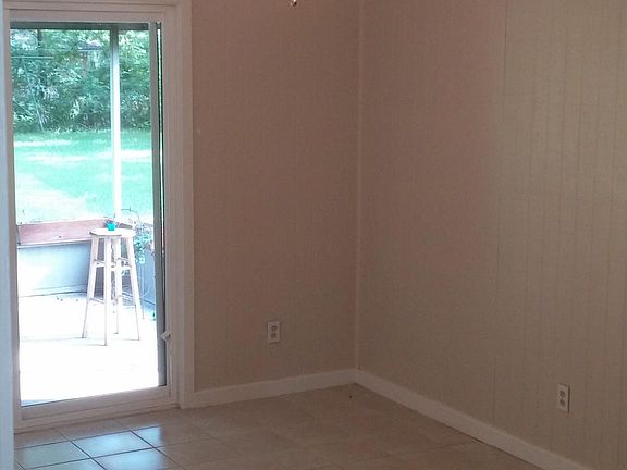 Dining area: tile flooring with painted wood paneling and painted wood ceiling. View through sliding glass door looks into covered porch and backyard beyond.