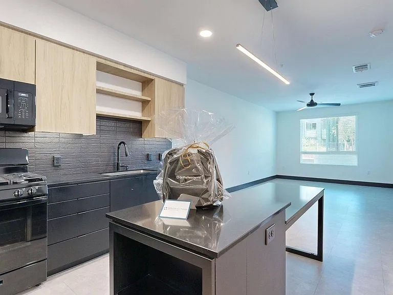 Apartment kitchen with black appliances, dark counters, and tile floor.