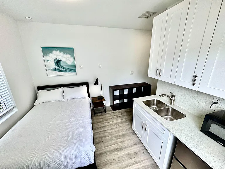 Efficient furnished sleeping area with a dedicated kitchenette, ample cabinetry, and easy-care flooring for daily living.