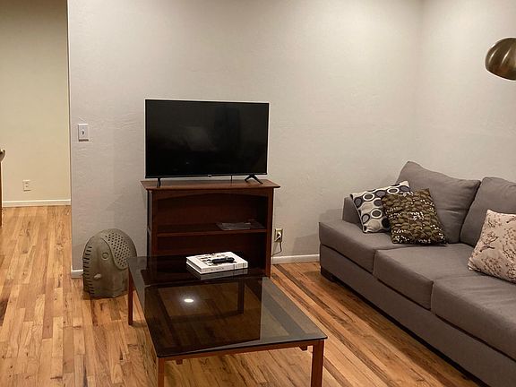 living room with TV, couch, desk, wood stove