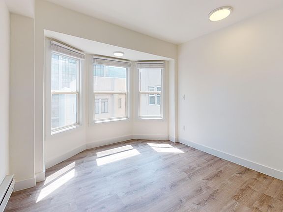 Bright, empty room with wooden floors. Features a bay window allowing abundant natural light.