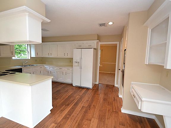 Kitchen offering hardwood laminate floors, built-in desk, pantry and a built-in microwave and oven