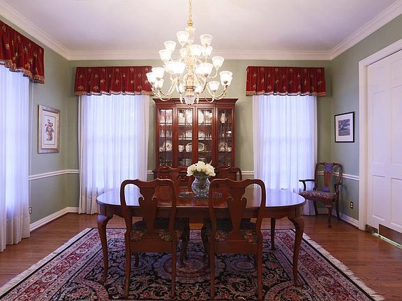 Formal dining room has crown molding, chair rail, and swing door that leads to the butlers pantry.  Triple brass chandelier and custom window treatments add to the dramatic feel of the room.