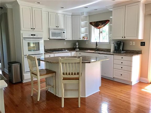 Gorgeous kitchen with plentiful cabinets, granite countertops, center island, double ovens, and hard