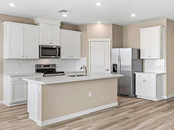 The kitchen has stainless appliances and plank flooring.