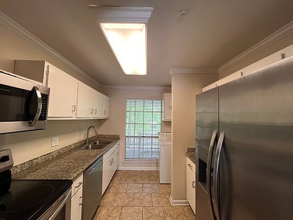The kitchen has a stainless steel stove, range, dishwasher, and French door refrigerator with a water and ice dispenser. The washer and dryer are included with the unit. There is also a pantry in the entryway to store food and appliances when not in use.