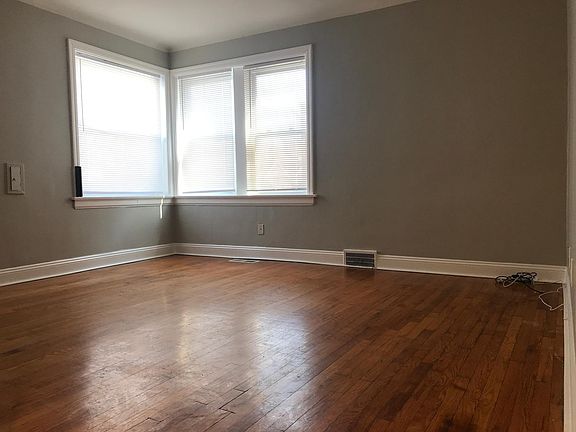 Living room, corner windows, mini-blinds, original hardwood floors. (grey)
