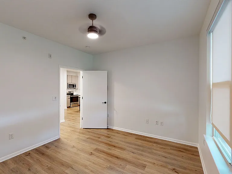 Spacious apartment bedroom with wood-style flooring.