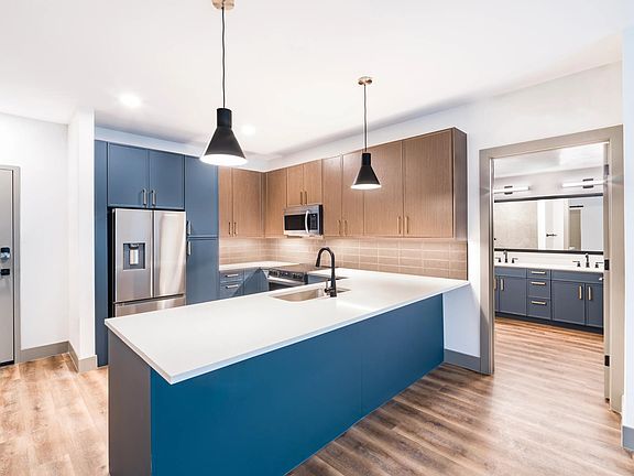 A clean, contemporary kitchen with bold cabinetry, generous counter space, and designer lighting.