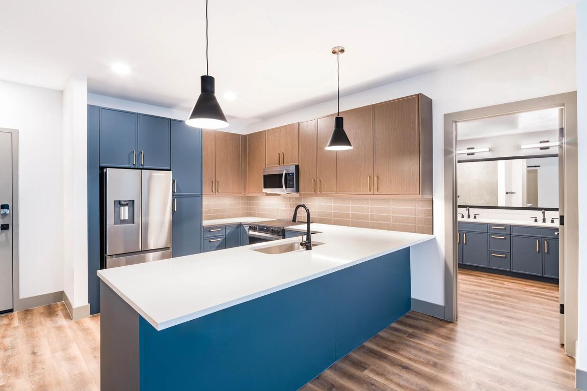 A clean, contemporary kitchen with bold cabinetry, generous counter space, and designer lighting.