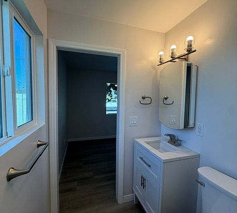 Alternative view of master bathroom highlighting the modern vanity, updated lighting, convenient storage, and bright window facing towards the private fenced in back yard.