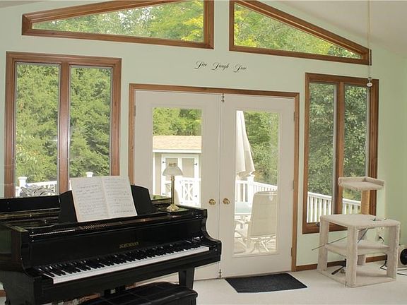 LARGE FLORIDA ROOM THAT LEADS TO NEW VINYL DECK OVERLOOKING WOODED BACKYARD