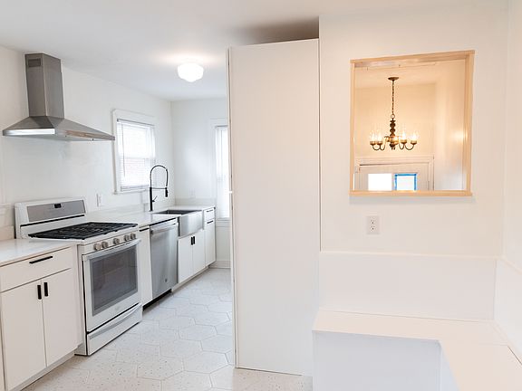View of kitchen with gas stove, new stainless steel appliances, and custom cutout to allow more light into the stairway and a view of side door.