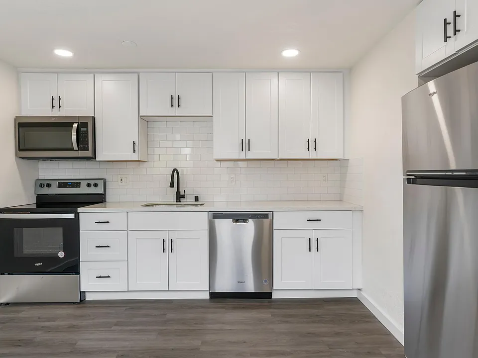 Full size Whirlpool appliances: fridge with built-in icemaker, oven, 4 burner range, microwave that vents outside, dishwasher, and garbage disposal. There is also pantry behind the fridge (not photographed).